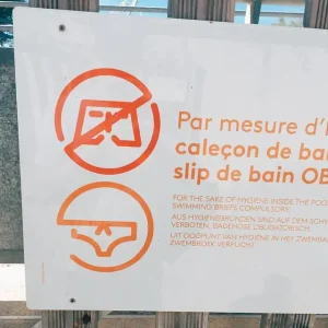 Swimming pool sign banning loose fitting men's swimwear